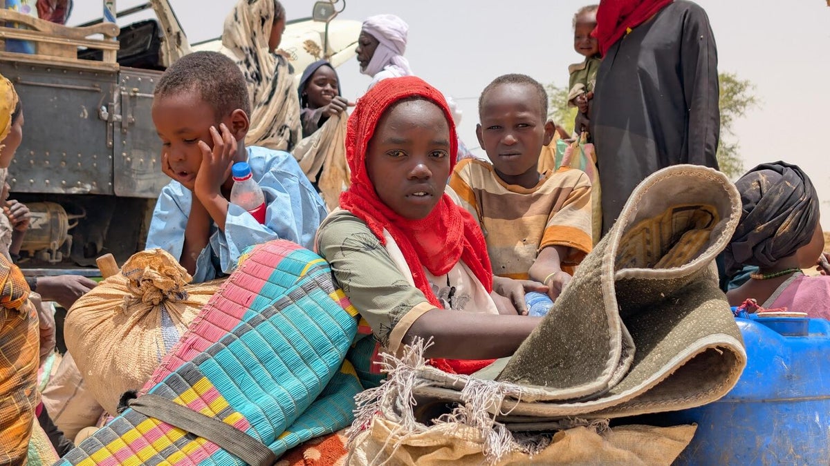 A group of children waiting to move to a temporary site for displaced people.