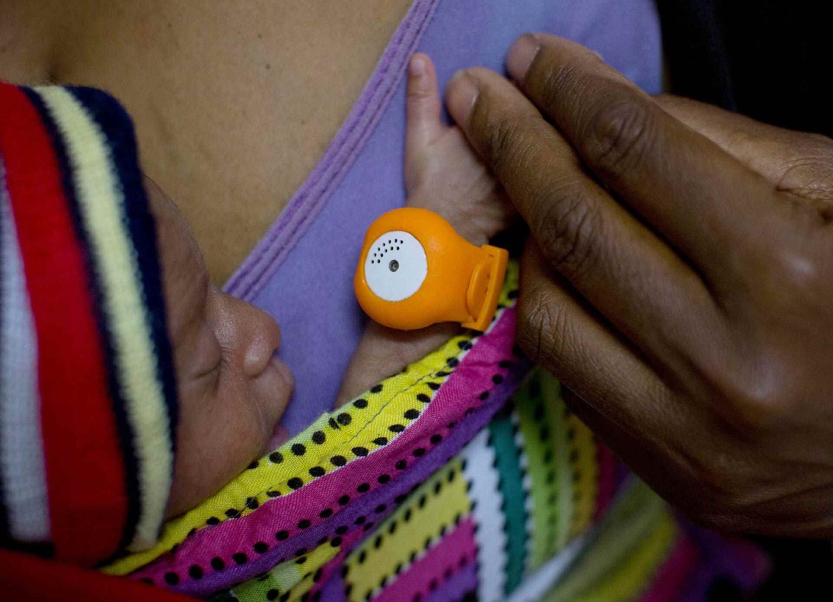 Baby Lauren wears an orange hypothermia alert device, locally dubbed the Bebi Kol Kilok ,while being cradled by her mother Ruth, at the neo natal unit in Southern Highlands Province, Papua New Guinea.