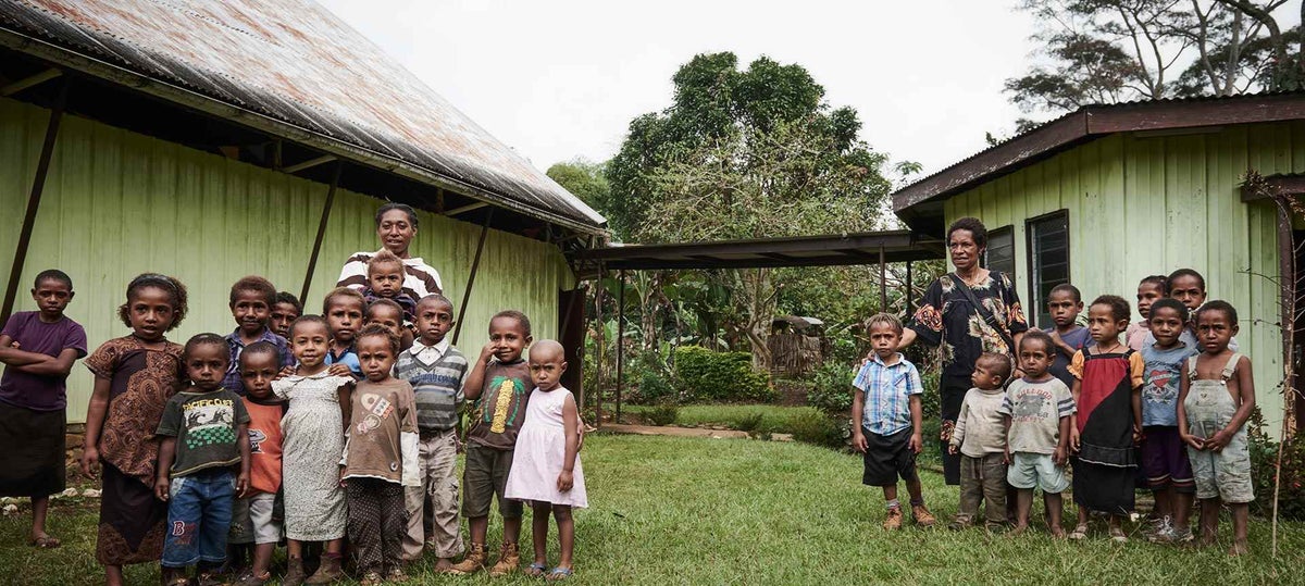 Children from two tribes in Siure, Chimbu, pose for a photo. The Kamaneku tribe (left) and the Silku Tribe have opposed one another for generations. The town’s road divides the land between the tribes