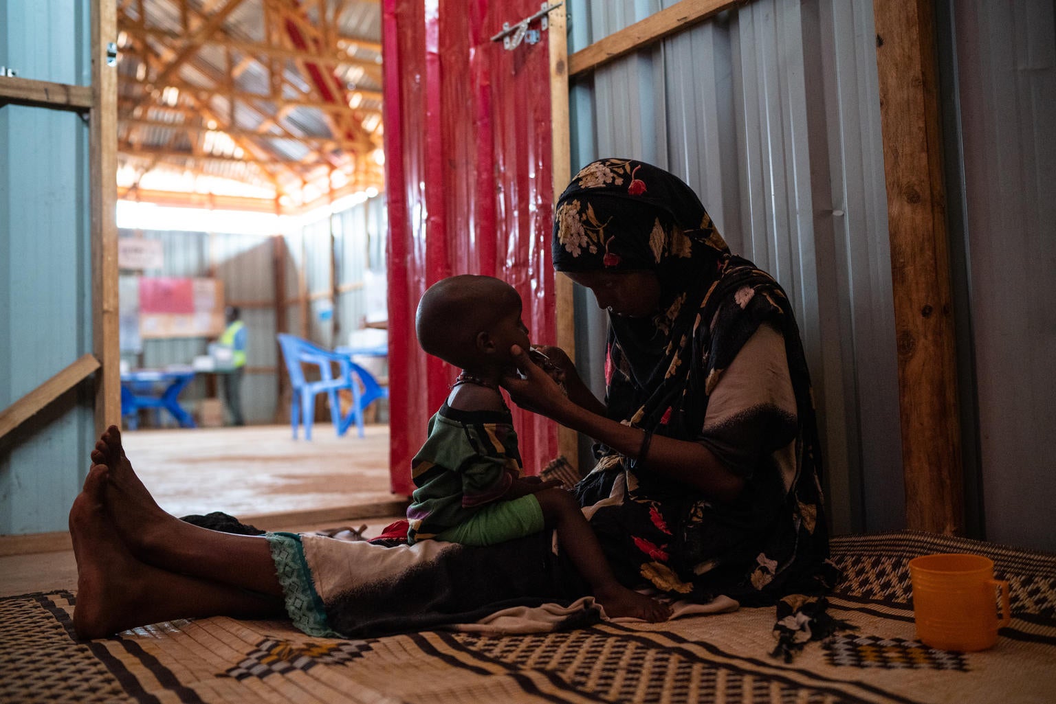 A young mother gives Ready-to-Use Therapeutic Food to her son who is suffering from Severe Acute Malnutrition