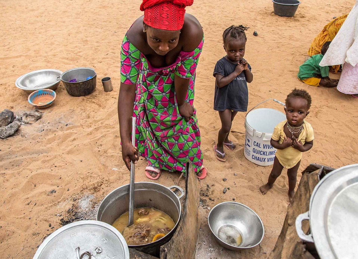 A mother prepares food for her family whilst her children look on. In Mauritania, one in four people are living in a situation of severe food insecurity