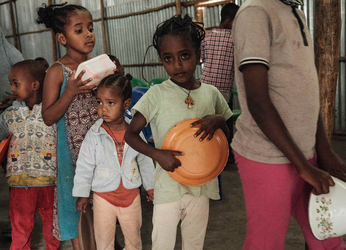 Children doing a line an holding plastic bowls.
