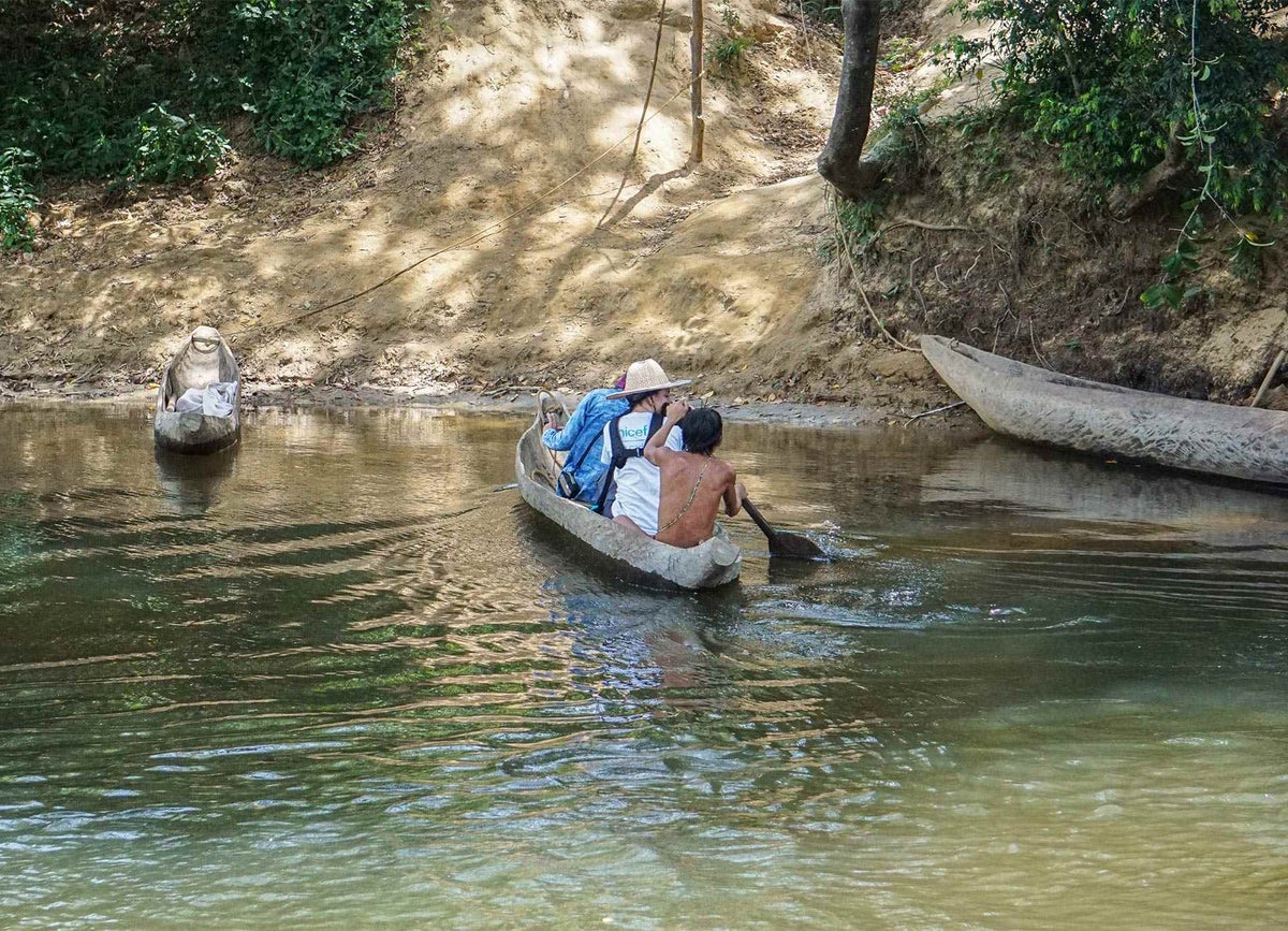 UNICEF staff ride in a “curiara” dugout canoe to visit the family homes of the Hoti ethnic group.