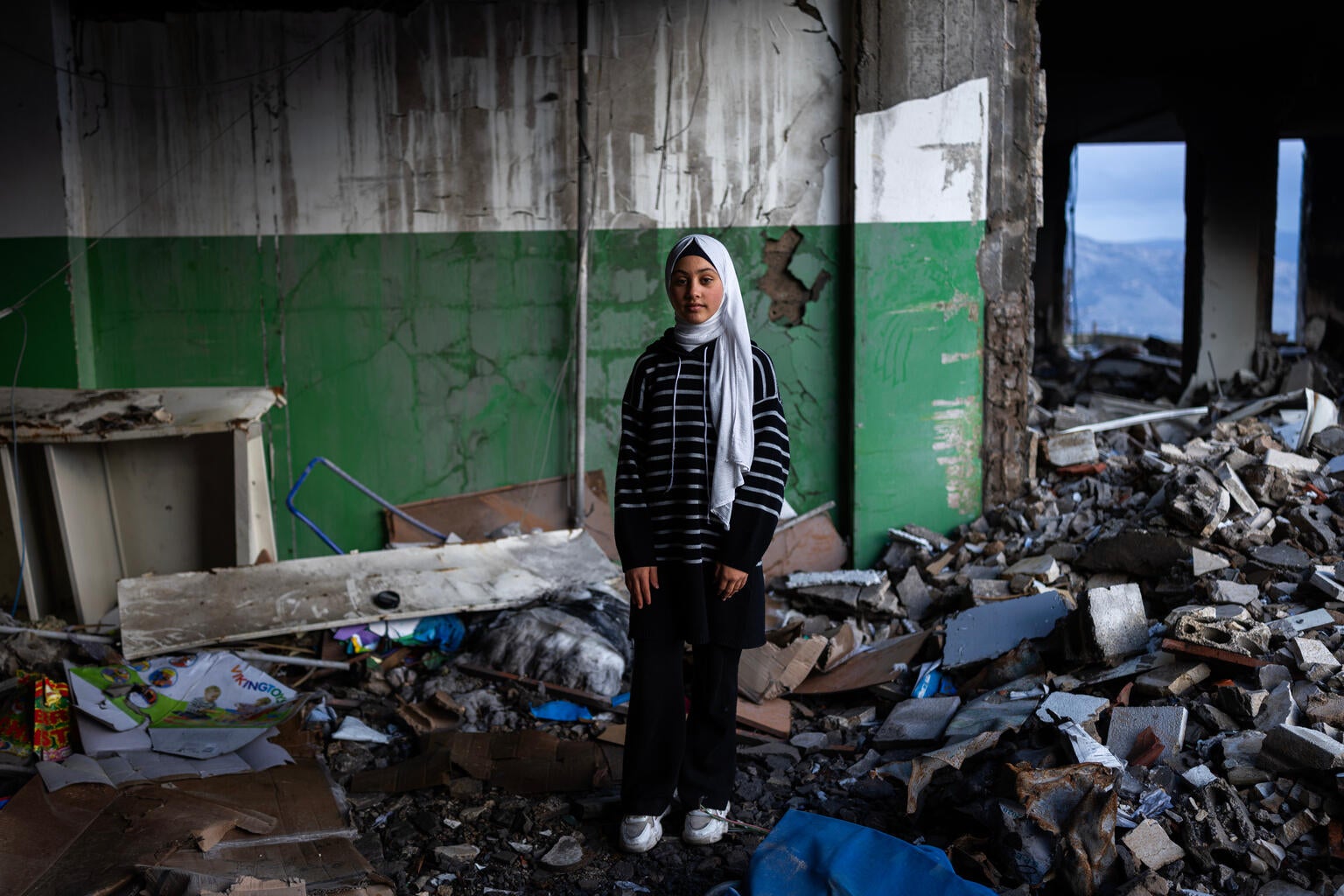 Young girl in Lebanon stands in her destroyed school