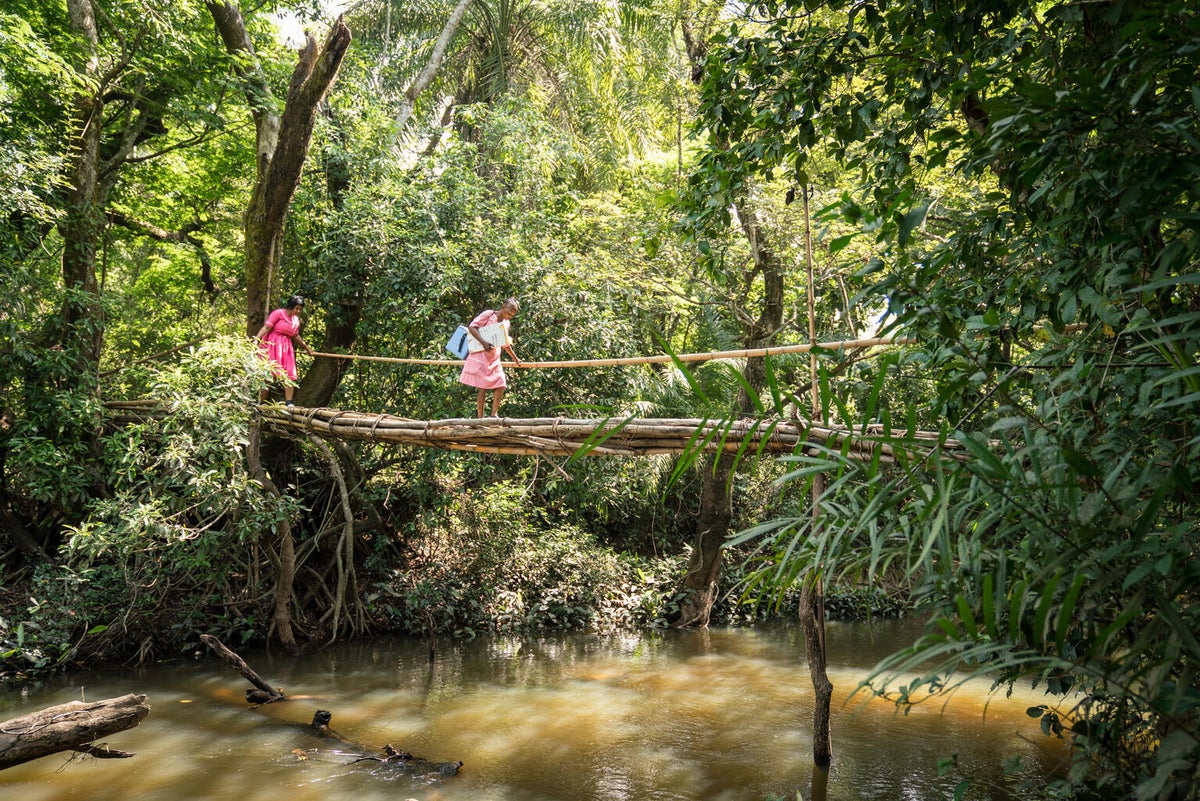 Two nurses crossing a bridge to the remote village of Mansunthu in Sierra Leone to conduct a mobile COVID-19 vaccination clinic.