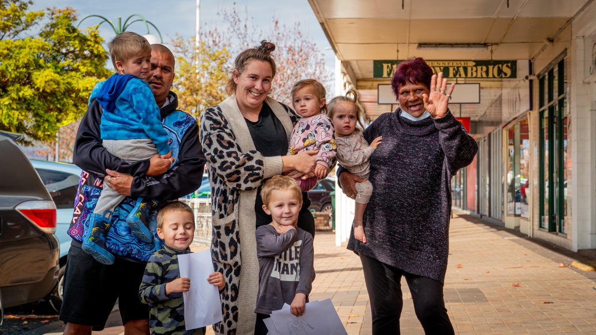 A family of three generations standing on the side of the road. 