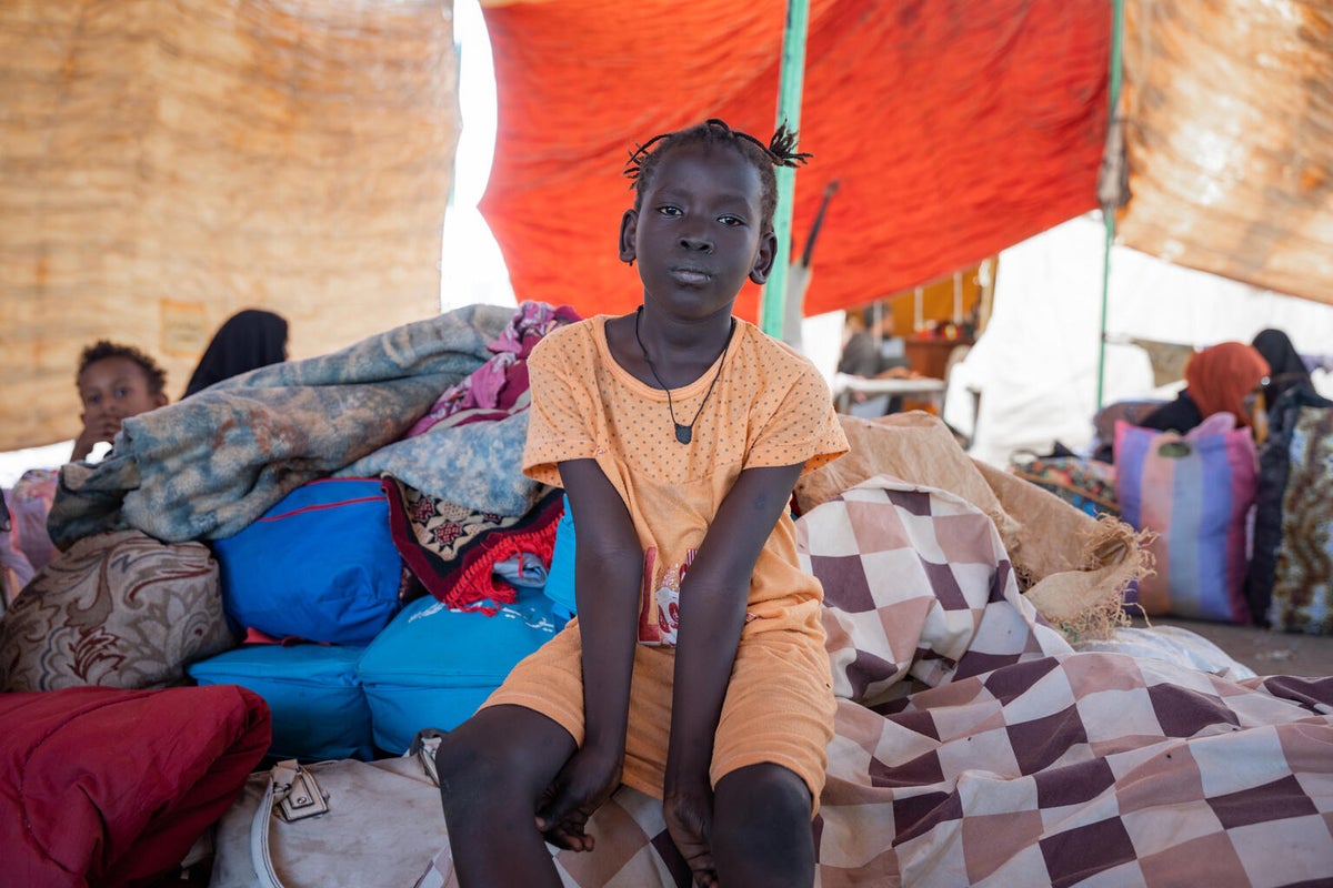 A girl sits in a makeshift tent.