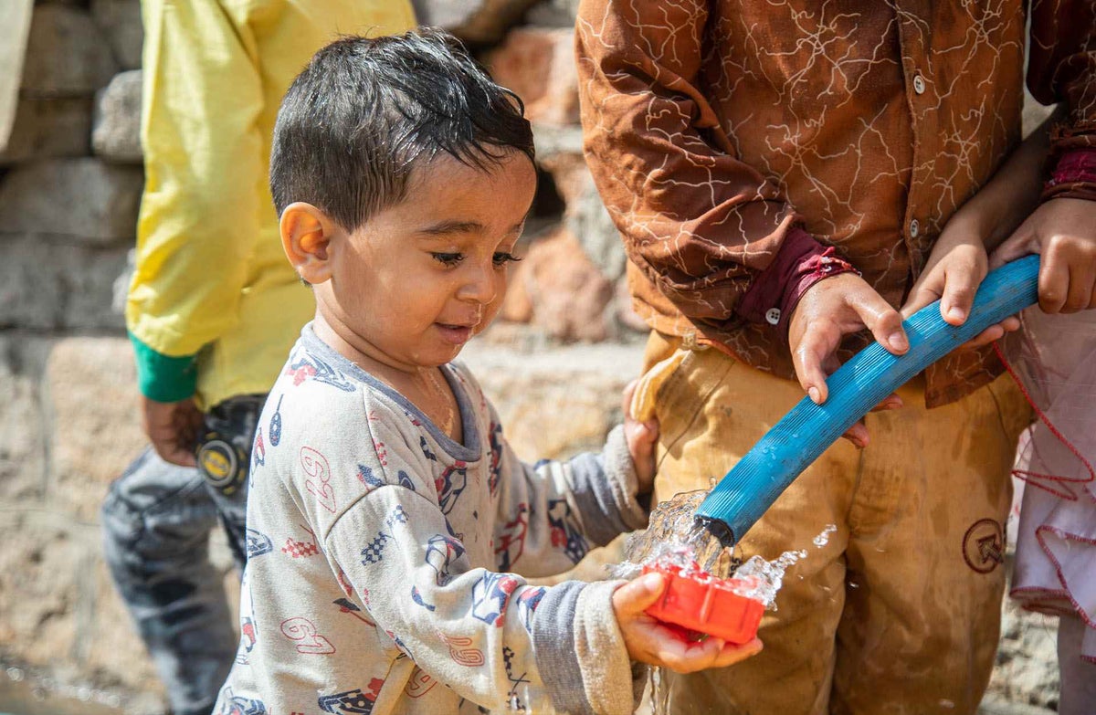 Rayan, two-and-a-half years old, celebrates the water’s arrival in his area.