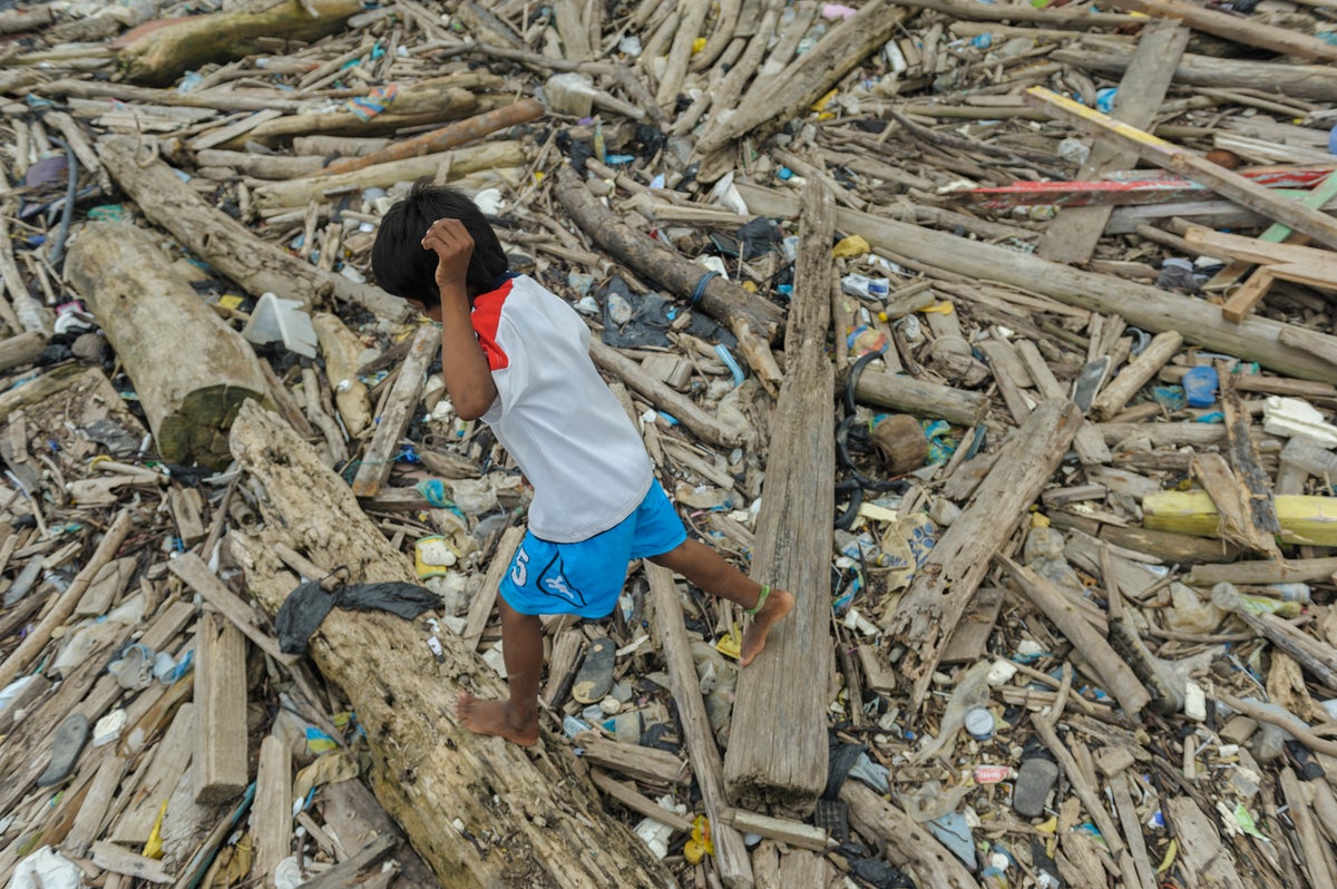 A boy walks barefoot over a pile of rubble.