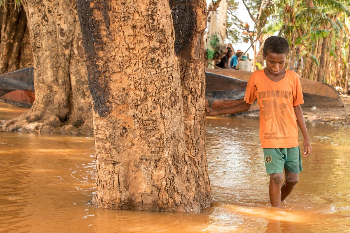 A boy walks through flooded terrain. The water reached above his ankles.