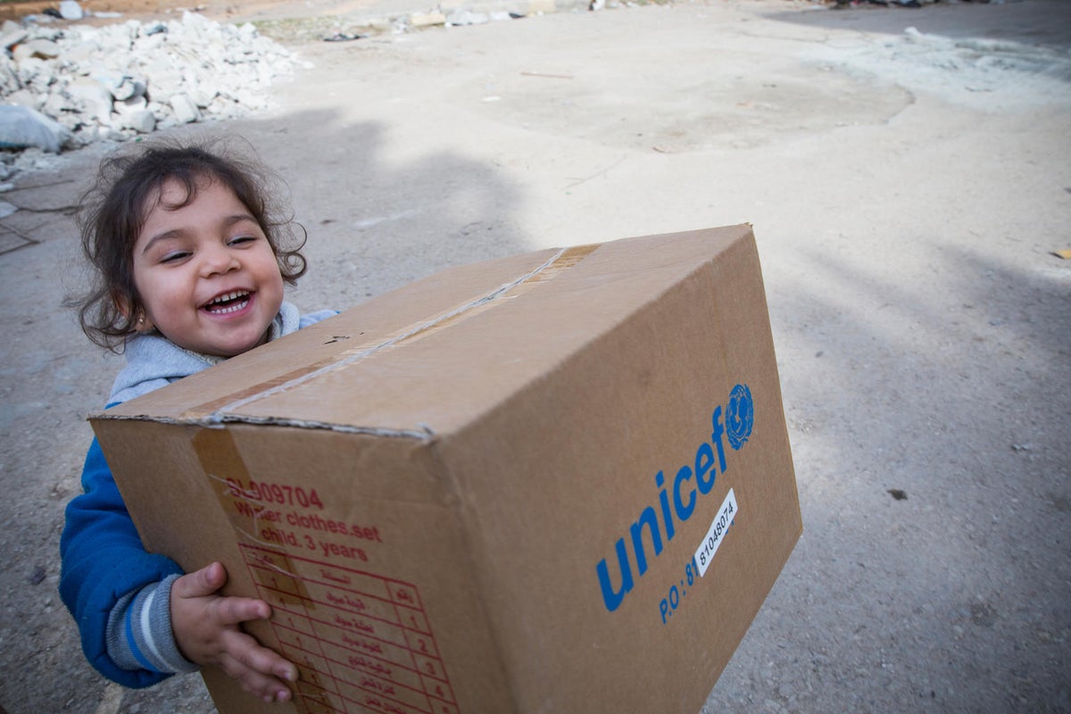 Happy Child in Syria carrying UNICEF supplies home 