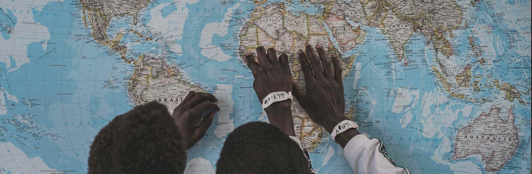 Hands pointing to Africa on a world map.