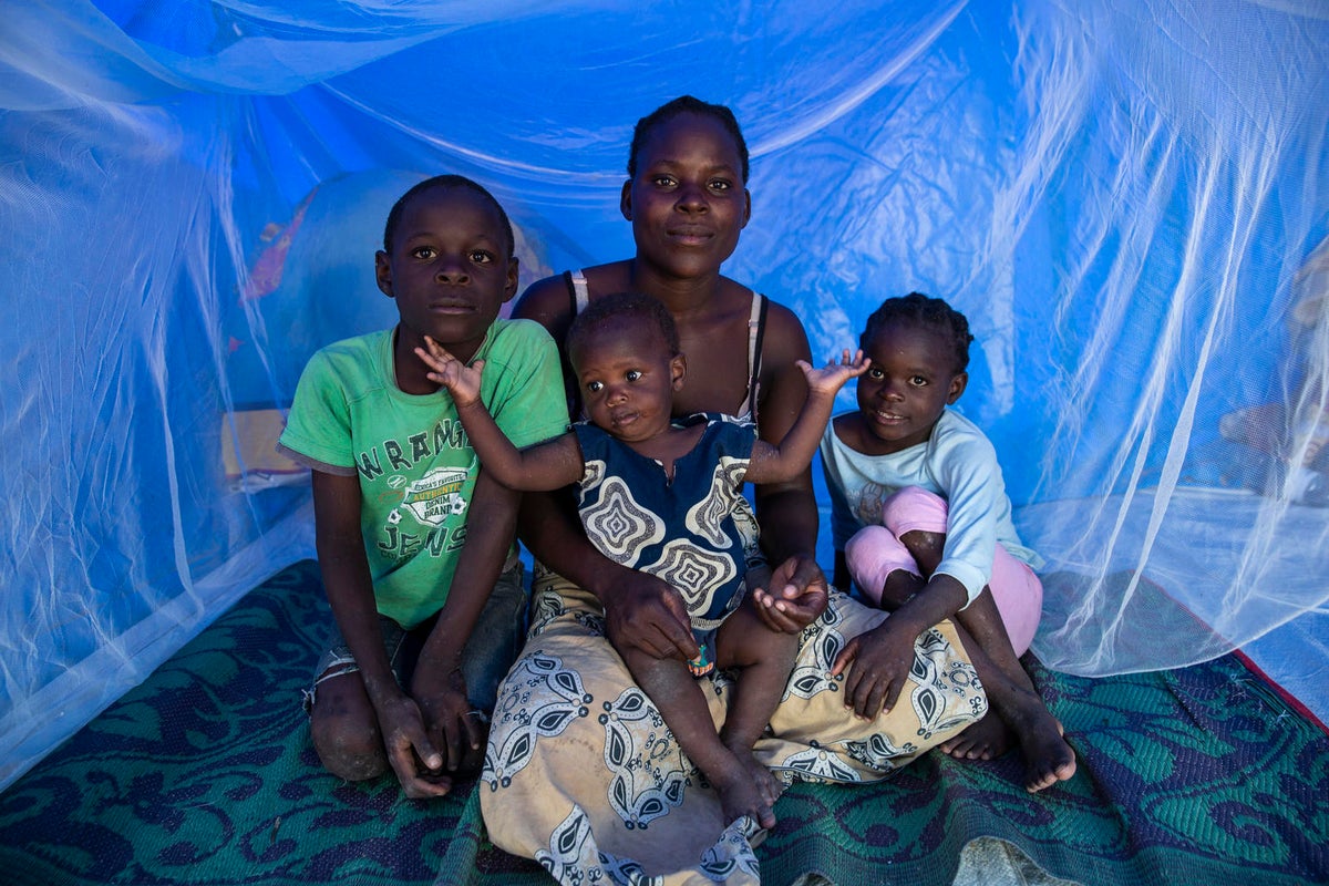 A woman with three children posed to the camera inside an aid tent.