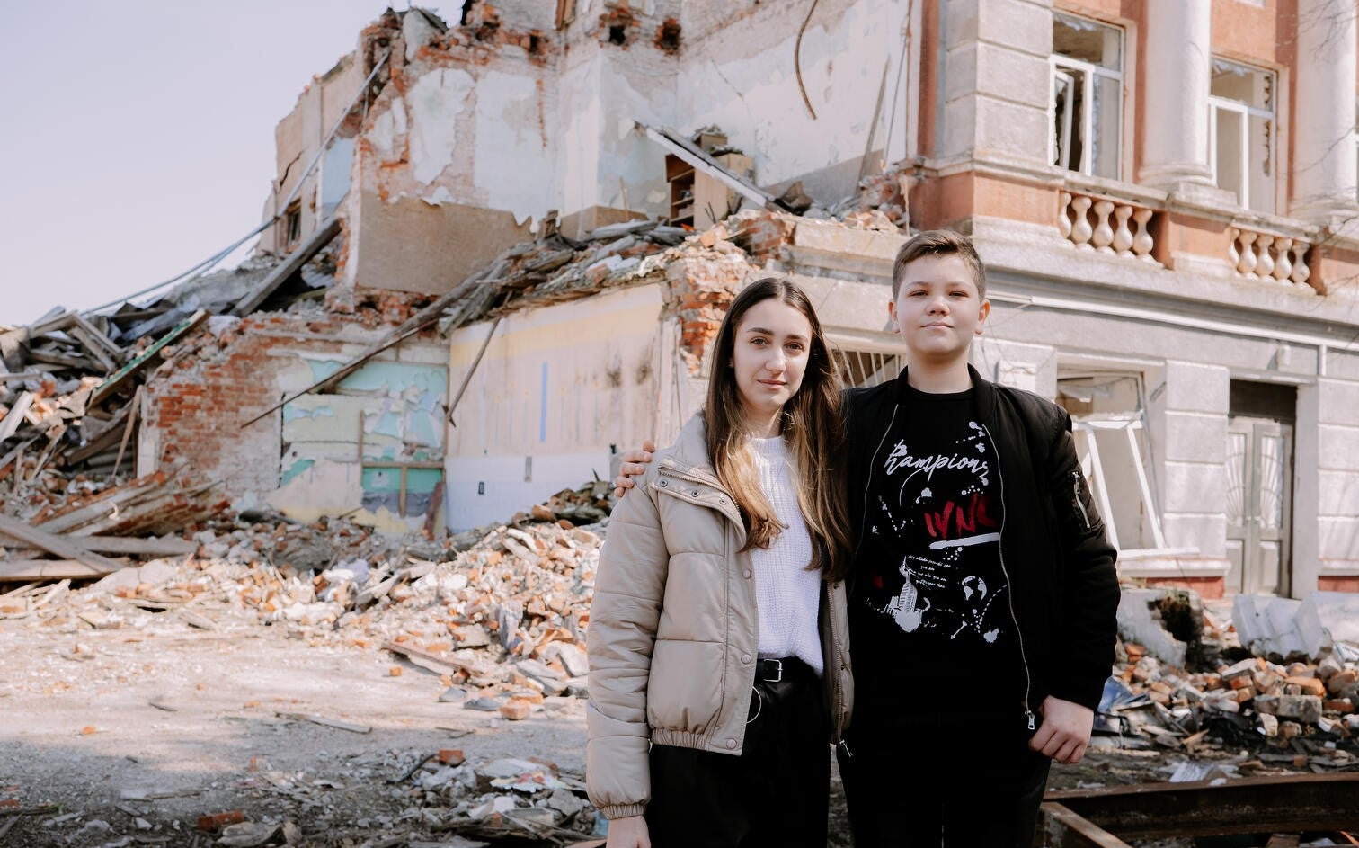 A brother and sister out the front of their destroyed home in Ukraine.