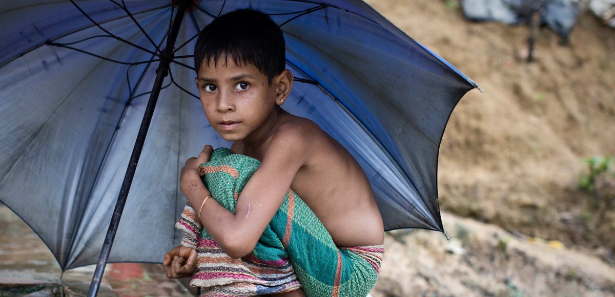 Child sits under umbrella