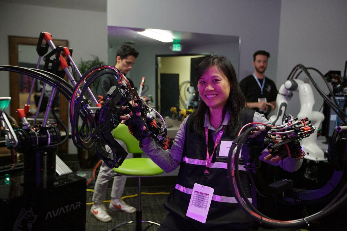 Peggy Wu, a woman wearing a black high-vis vest, has her hands in a robotic interface