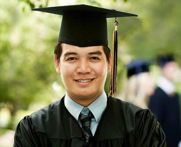 A young man in a graduation cap and gown after receiving a military spouse scholarship.