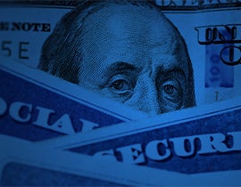Close-up of Benjamin Franklin’s face on a U.S. $100 bill, partially covered by Social Security cards in blue lighting.
