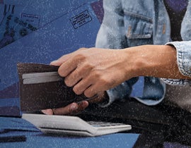 Image of a person opening a wallet while using a calculator.