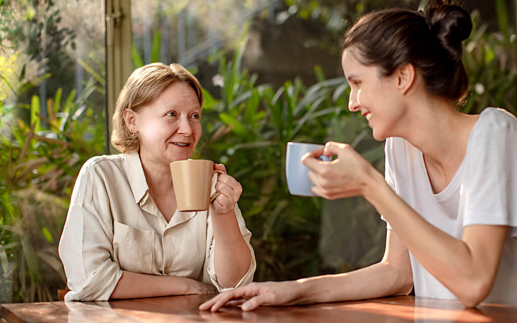 An image of an older woman and a younger woman drinking coffee.