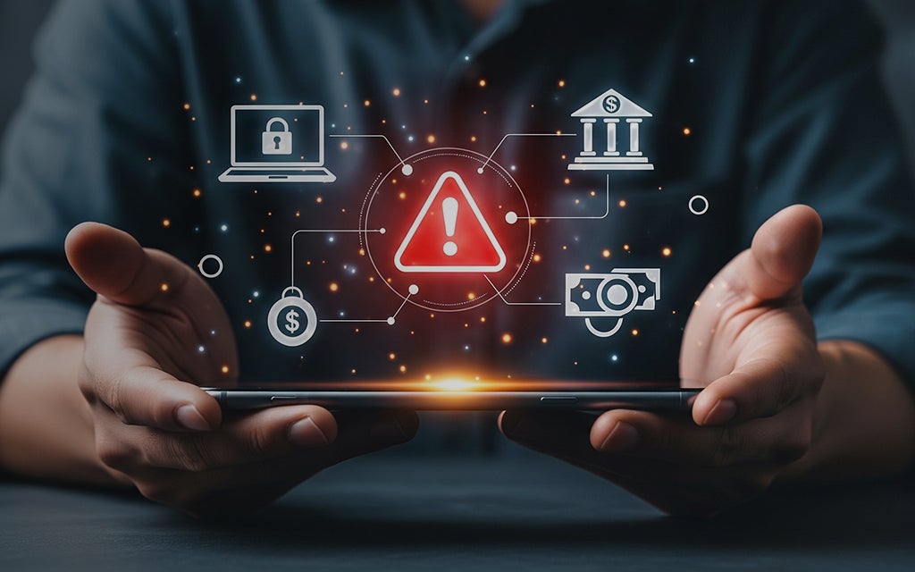 Hands holding a digital warning symbol surrounded by banking, lock, and security icons representing financial fraud and cyber risk