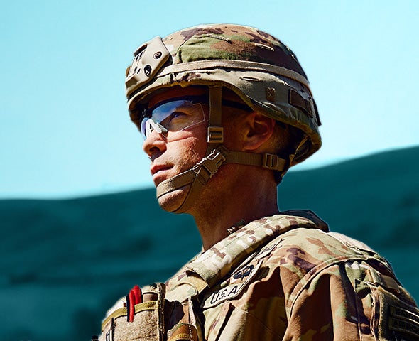 profile shot of man in military uniform in the field, mountains in the background
