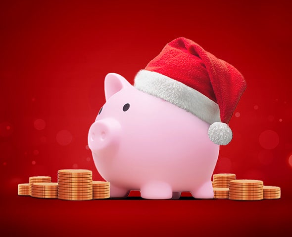 piggy bank in a santa hat surrounded by stacks of coins