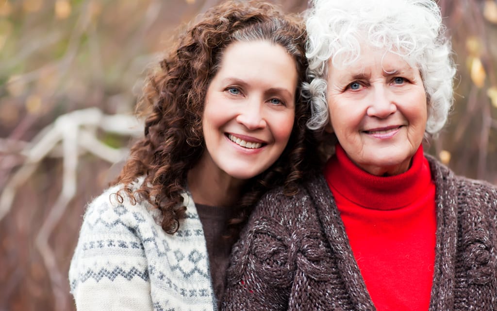 Middle aged female embracing an elderly women