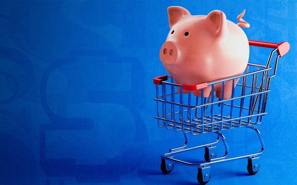 piggy bank riding in a grocery cart with dollar signs in the background