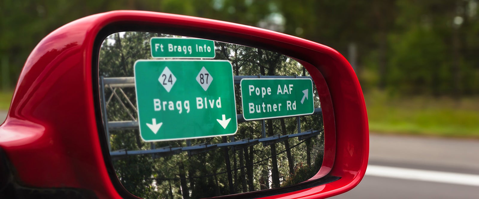 Road signs visible in the side mirror of a vehicle during a PCS.