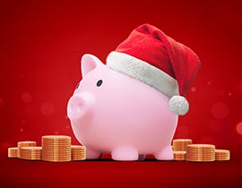 piggy bank in a santa hat surrounded by stacks of coins