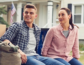 Image of a young man and women sitting outside their home.