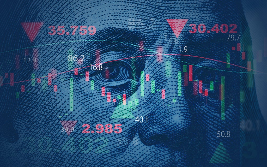 Close-up of Benjamin Franklin’s face from U.S. $100 bill overlaid with red candlestick charts, downward arrows, and financial data, symbolizing economic trends and projections for the year ahead.
