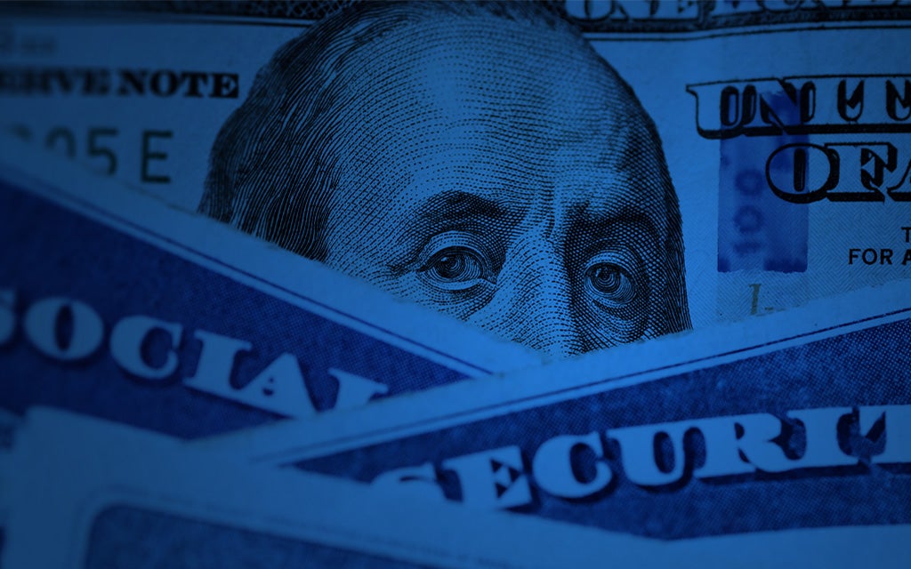 Close-up of Benjamin Franklin’s face on a U.S. $100 bill, partially covered by Social Security cards in blue lighting.