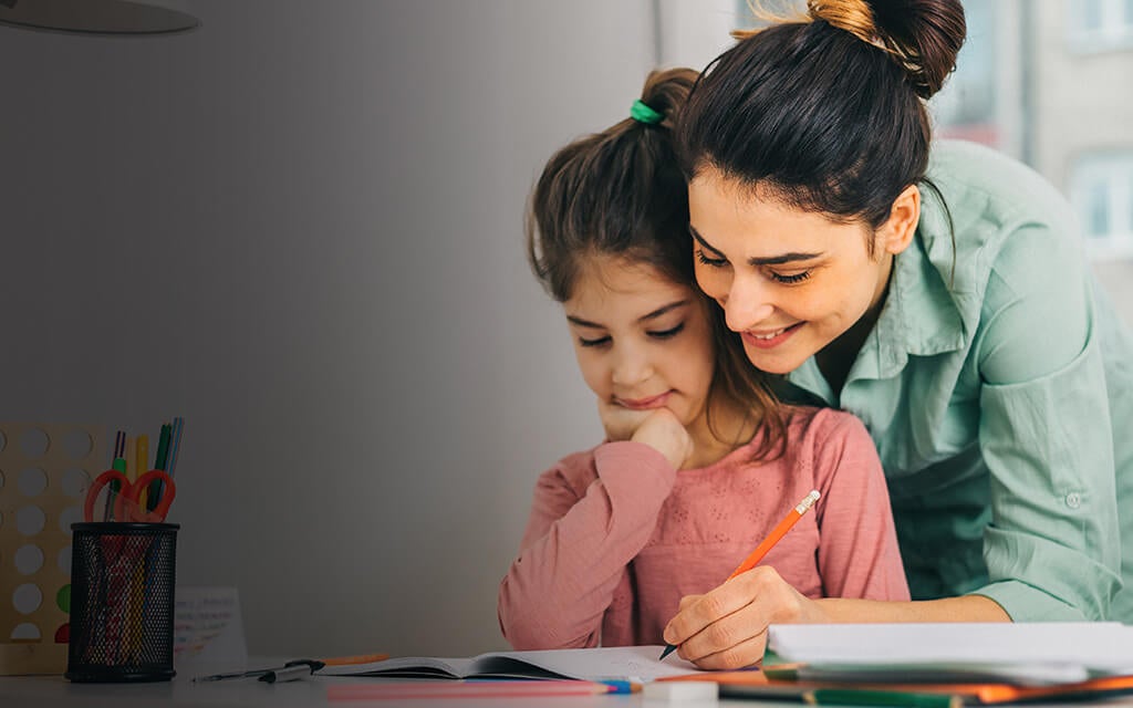 A mom helping out her daughter with homework.