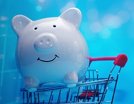 Piggy bank riding in a shopping cart with a blue background.