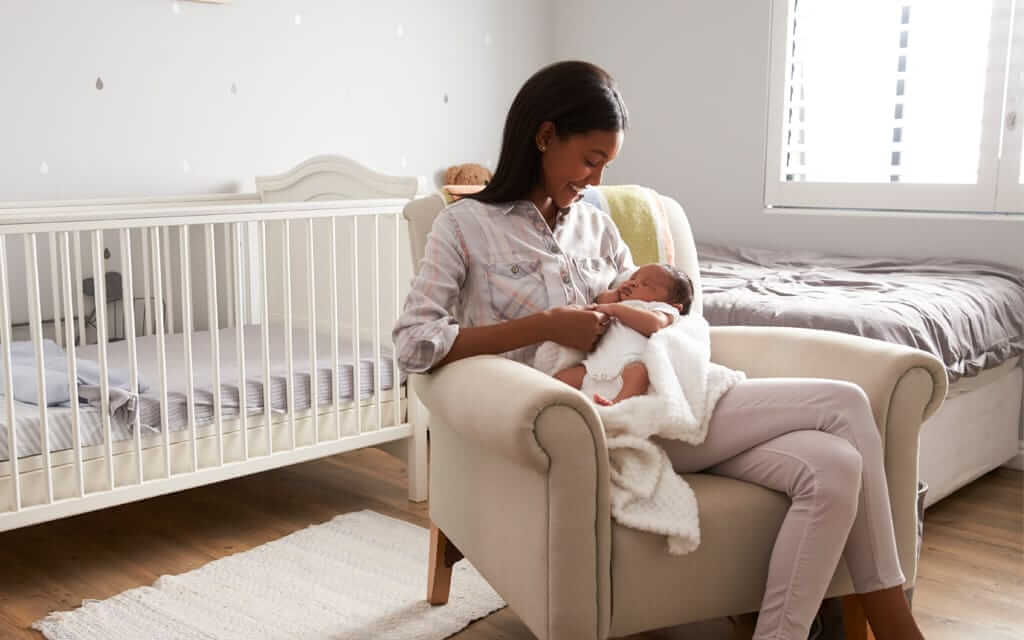 Mother holding sleeping new born in a chair