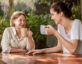 An image of an older woman and a younger woman drinking coffee.