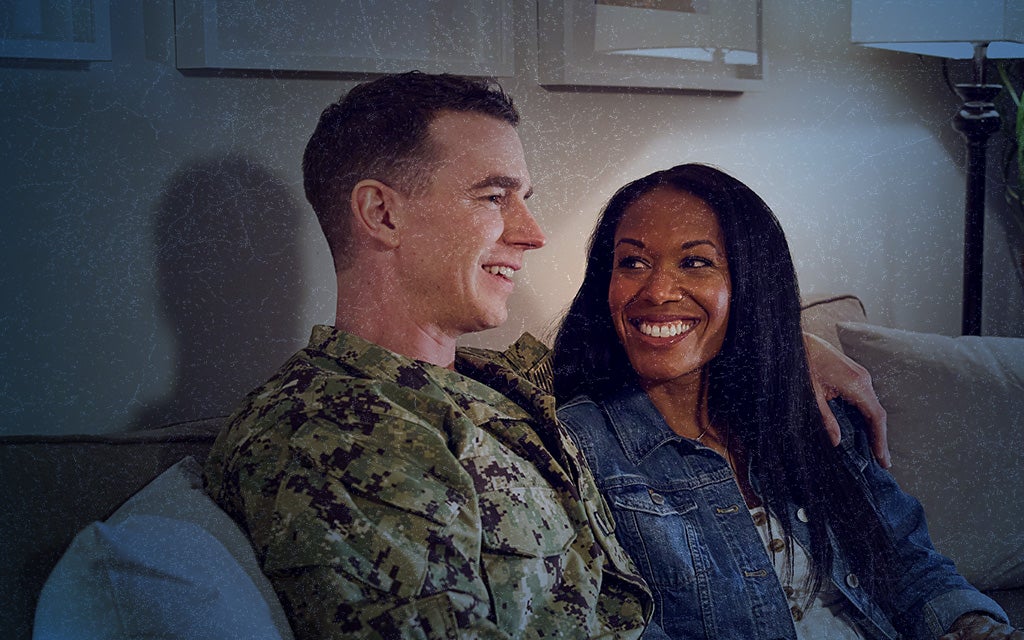 service member and their partner sitting closely on a couch, smiling