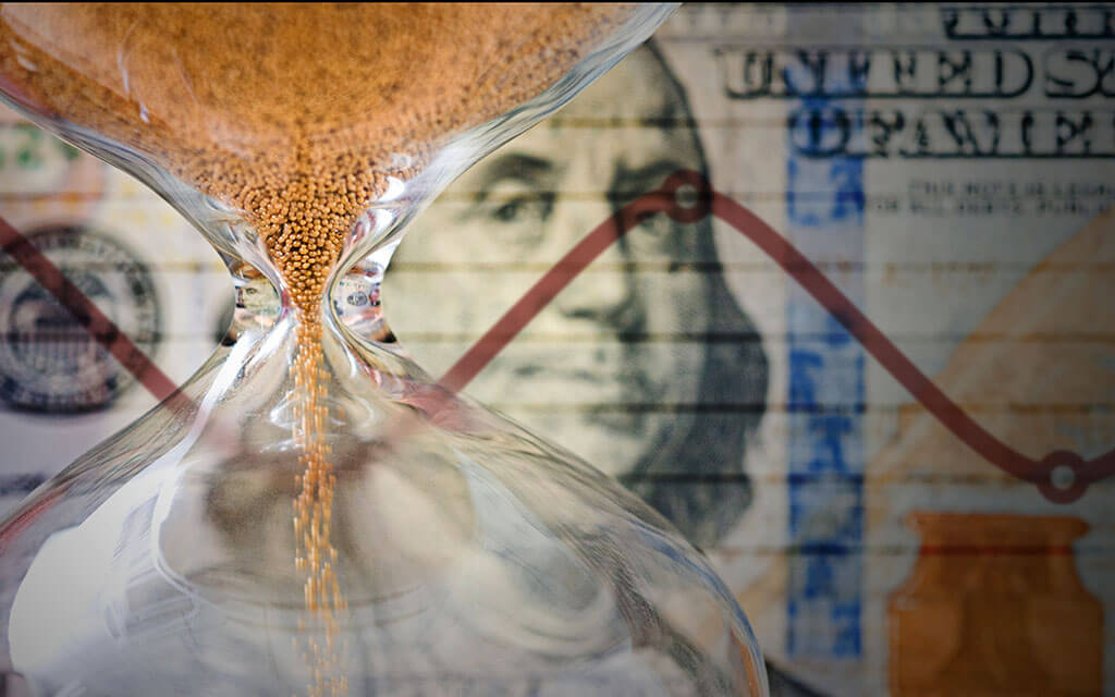 An image of a hourglass up-close with money in the background.