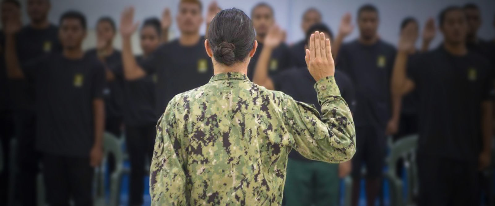 A group of young soldiers raising their hands during a military enlistment ceremony.