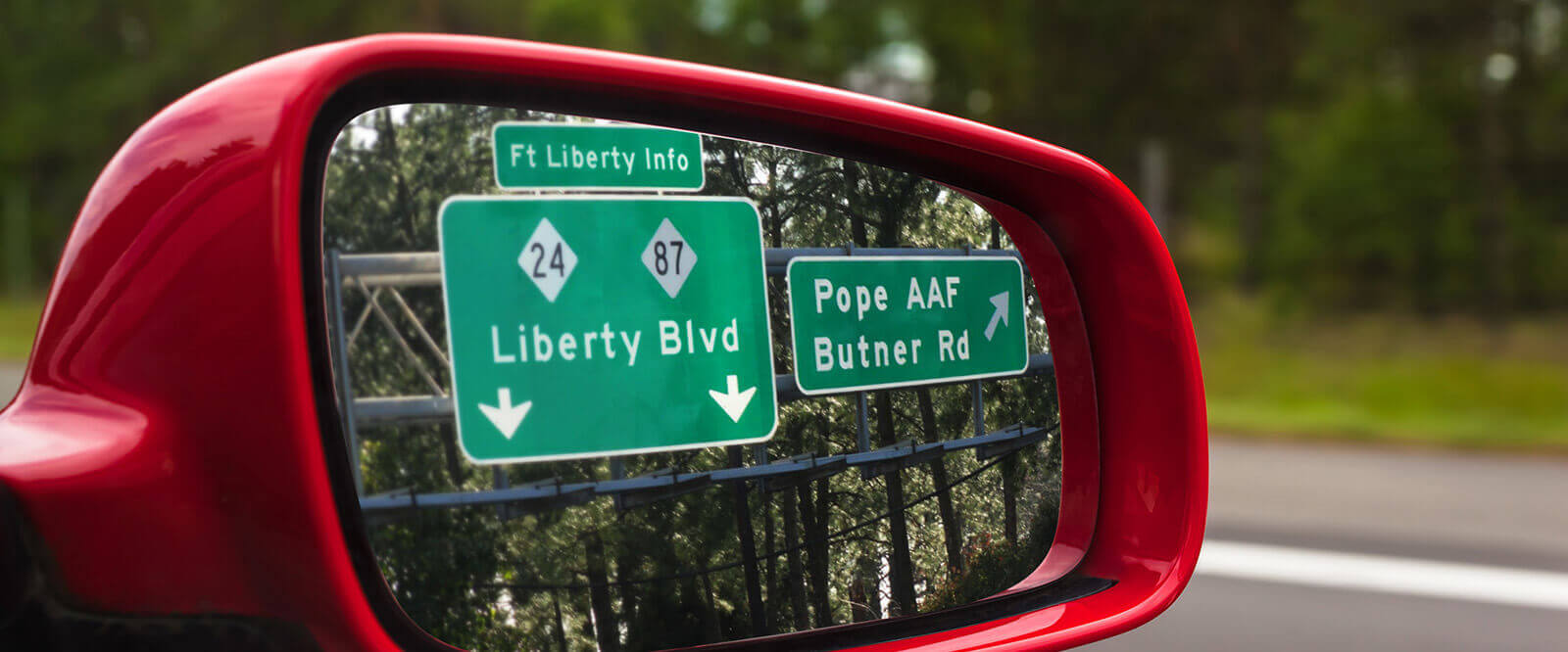 Road signs visible in the side mirror of a vehicle during a PCS.