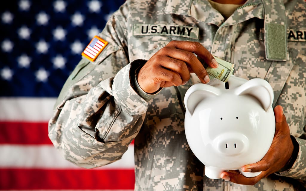 Army personnel putting money in to a piggy bank