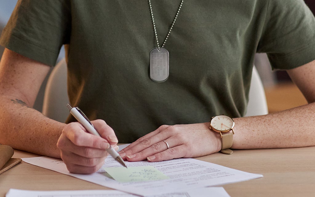 person sitting at a table signing paperwork