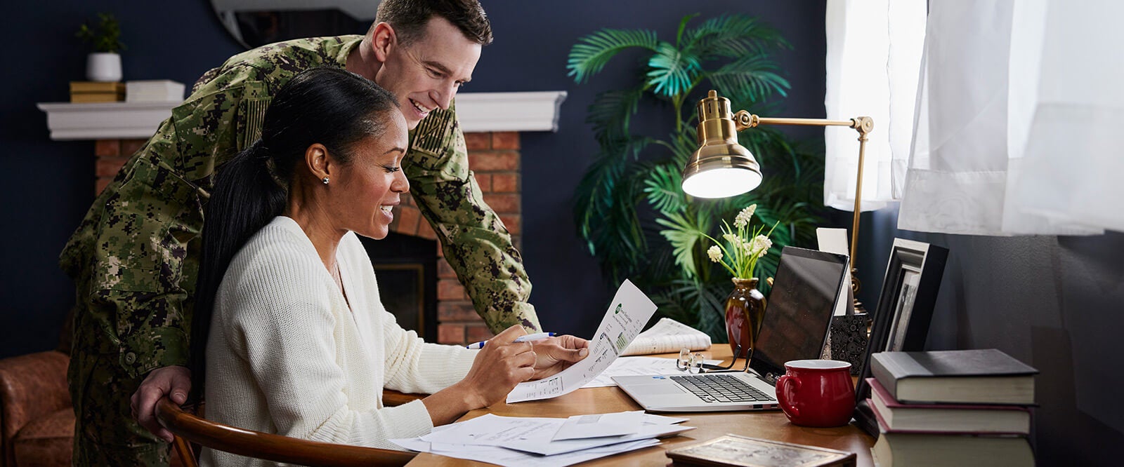 A smiling soldier looking over military spouse benefits documents with his wife.