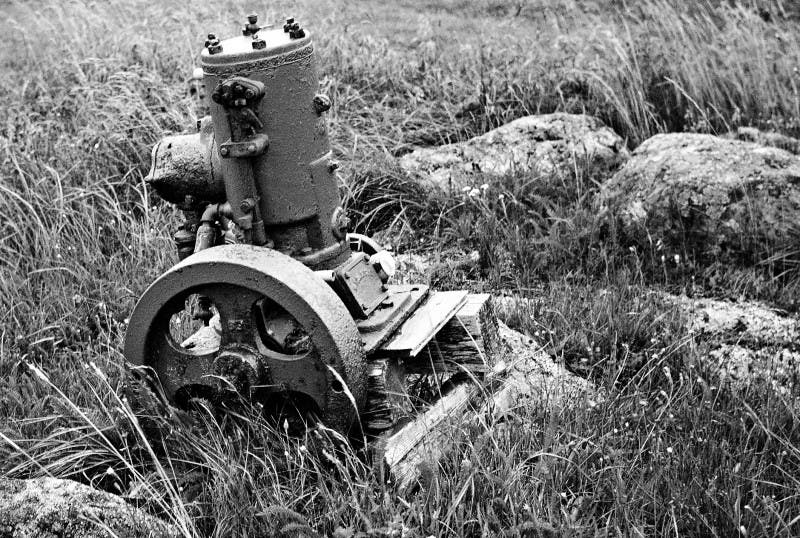 Discarded make-and-break engine in a field, St. Brendan’s Island, Newfoundland (photo by T. Rand Collins on throughavintagelens.com)