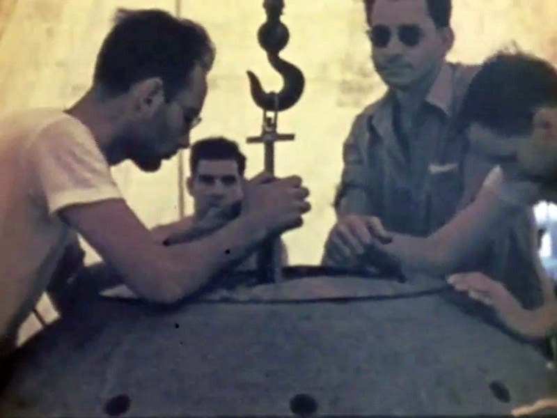 Assembling the Trinity “gadget” on the tower at the Trinity site in New Mexico; Harry Daghlian’s face is at center rear, photograph, ca July 15, 1945 (Wikimedia commons)