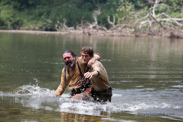 Still frame from the film The Lost City of Z, showing a hapless James Murray (played by Angus Macfadyen) being rescued by Henry Costin (Robert Pattinson), 2016 (moviestillsdb.com)