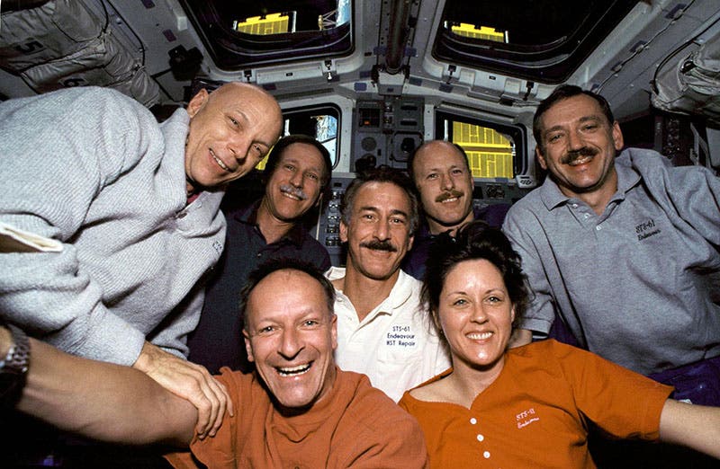 The crew of STS-61 in space; Richard Covey, mission commander, is at center; the woman, Kathryn Thornton, was one of the mission specialists who installed the corrective package COSTAR and the new camera WFPC2. The solar panels of the Hubble telescope are visible through the windows (appel.nasa.gov)