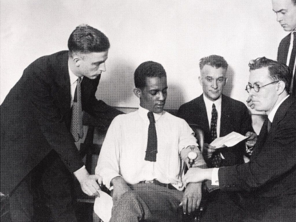 William Marston, right in glasses, administering his deception test to James Frye in a reenactment. Looking on from left to right are attorneys Lester Wood, James Bilbrey, and Richard Mattingly. Image source: Alder, Ken. The Lie Detectors: The History of an American Obsession. Free Press, 2007.